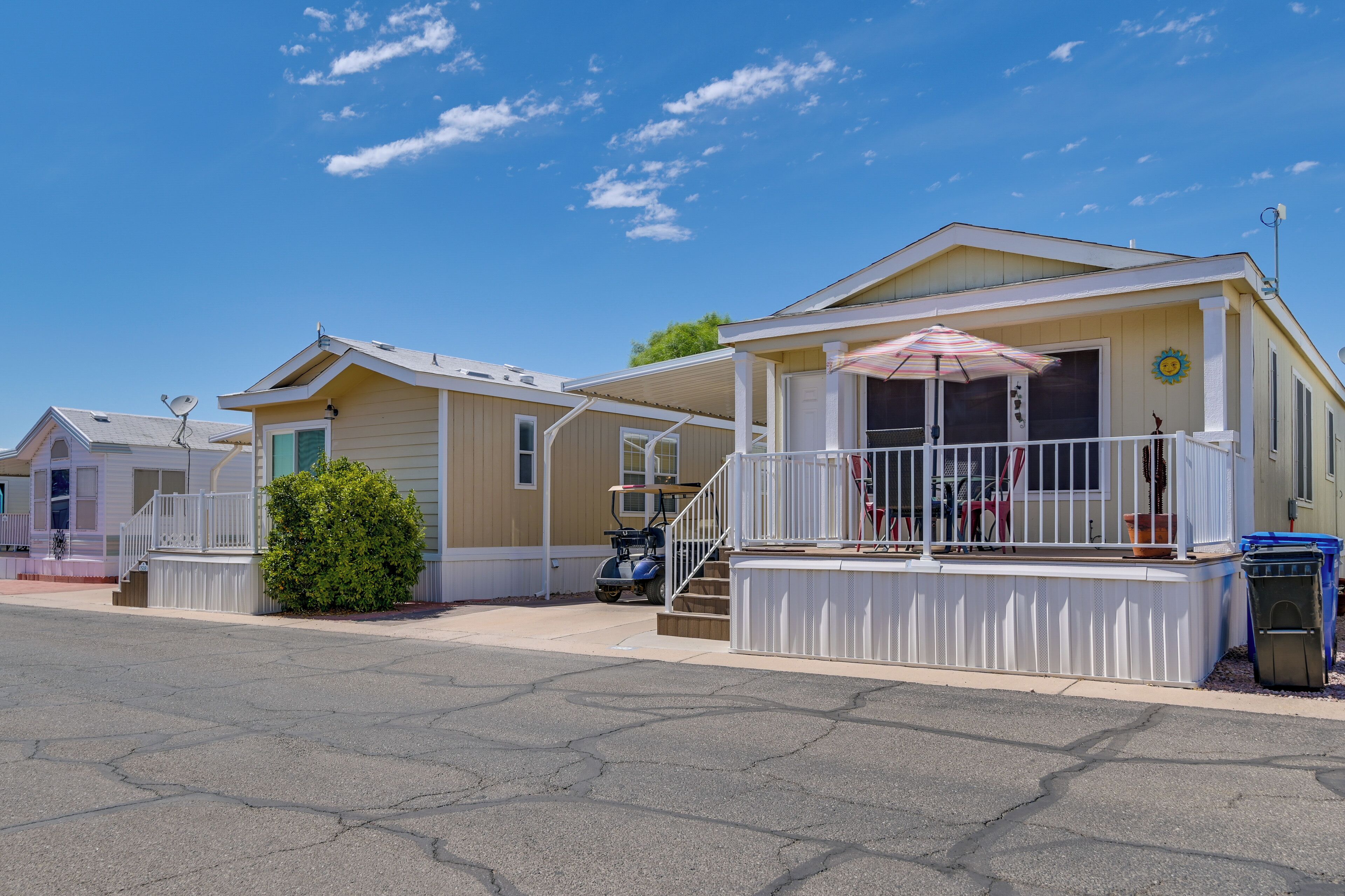 A row of mobile homes with a covered porch and a small garden area.