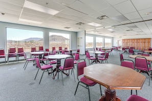 A conference room with tables and chairs, large windows with a desert view, and a carpeted floor. - Complimentary Golf Cart! Viewpoint Resort Home (Mesa)
