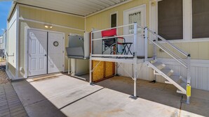 A building with a covered entrance, a set of stairs, and a door with a clock. - Complimentary Golf Cart! Viewpoint Resort Home (Mesa)