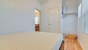 A bedroom with a bed, a door, a window with blinds, and a wooden floor. - Complimentary Golf Cart! Viewpoint Resort Home (Mesa)