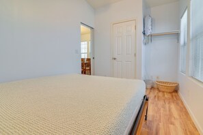 Ein Schlafzimmer mit einem Bett, einer Tür, einem Fenster mit Jalousien und einem Holzboden.