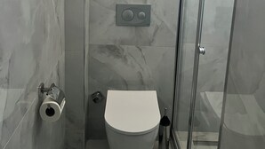 A bathroom with a toilet, a shower, and a glass door. - SESSE OTEL (Istanbul)
