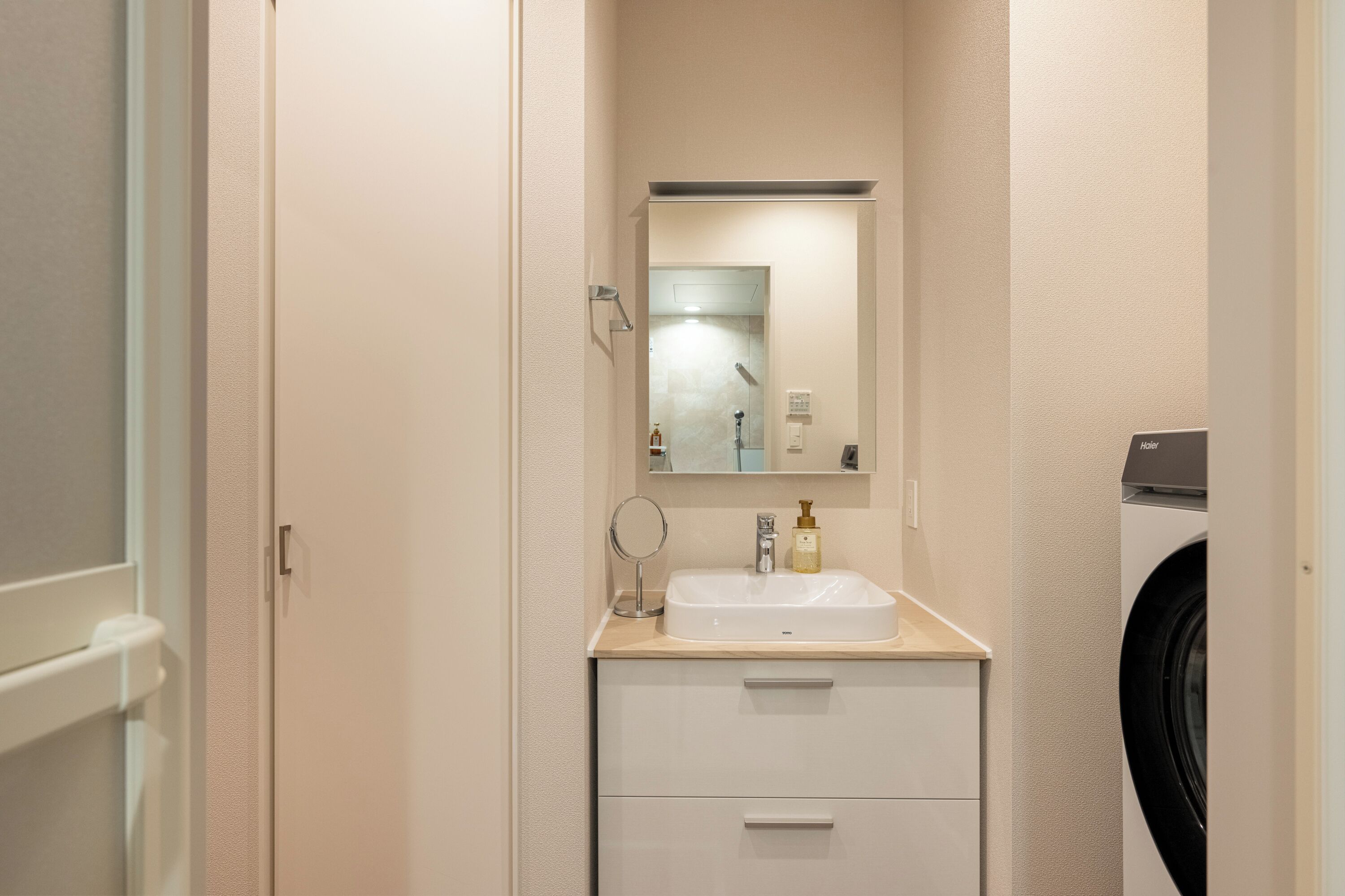 Un baño pequeño con lavamanos, espejo y un armario de almacenamiento.