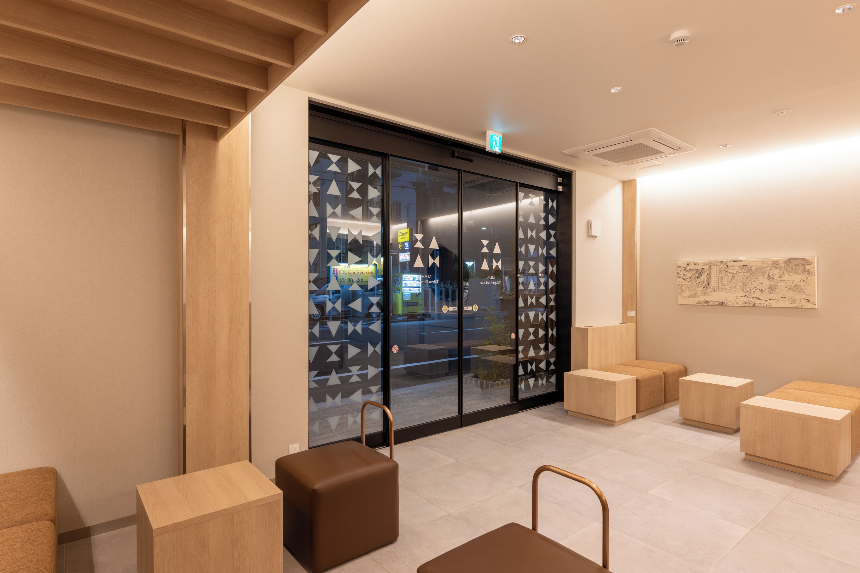 A modern interior with a reception desk, seating area, and a glass door with geometric patterns.