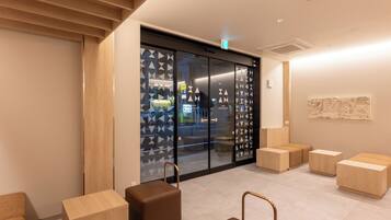 A modern interior with a reception desk, seating area, and a glass door with geometric patterns.