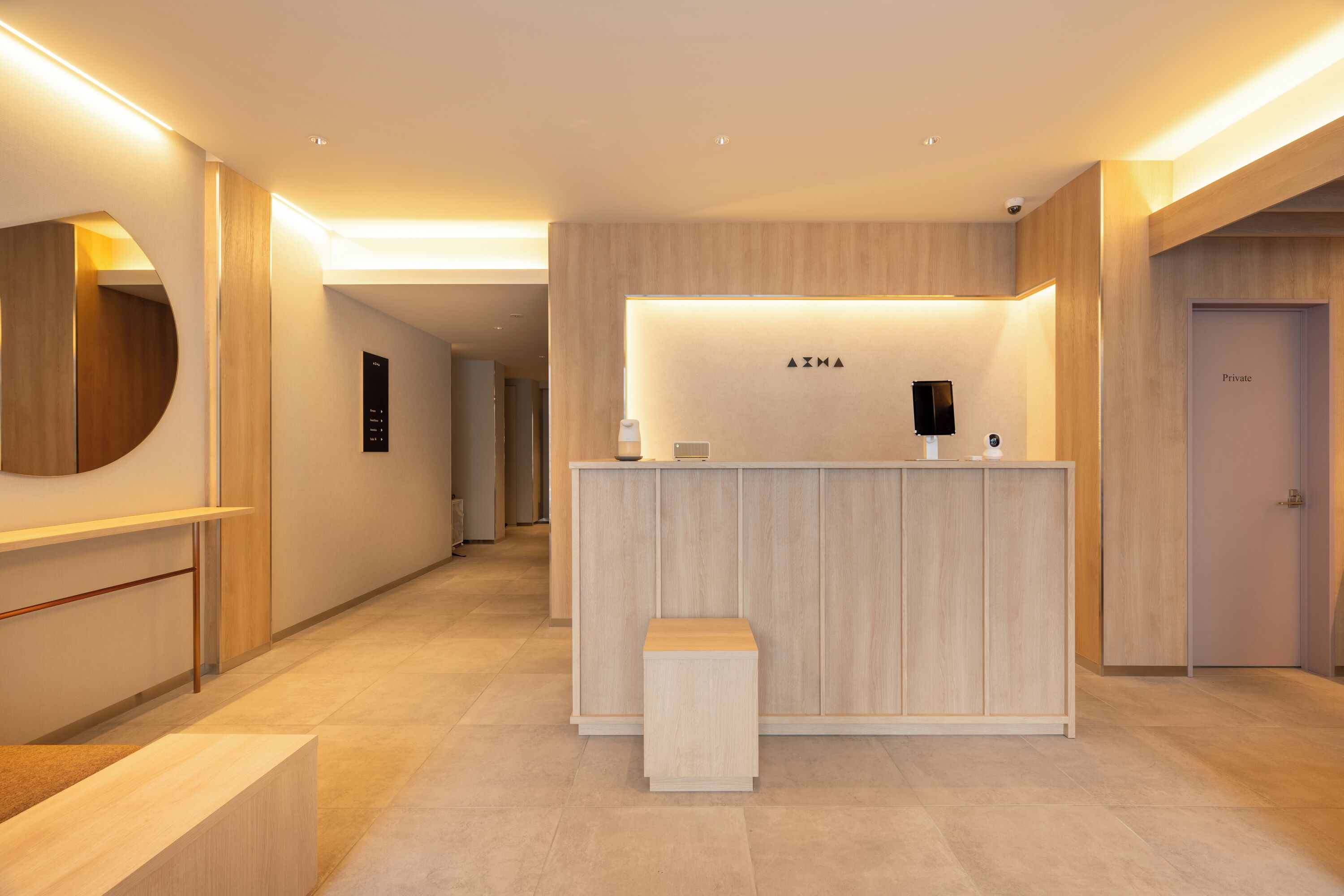 A modern reception desk with a wooden finish, a small bench, and a wall-mounted information board.