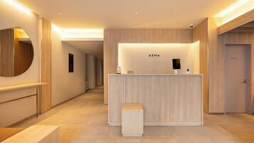 A modern reception desk with a wooden finish, a small bench, and a wall-mounted information board.