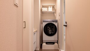 Une buanderie équipée d’un lave-linge et d’un sèche-linge à chargement frontal, d’une étagère pour les serviettes et d’une porte avec une serrure.