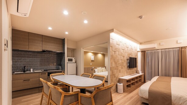 Une chambre d’hôtel moderne dotée d’un coin repas, d’une kitchenette et d’un grand lit.