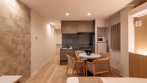 Une chambre d’hôtel compacte comprenant un coin cuisine, un espace repas avec une table et des chaises, et un lit.