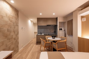 A compact hotel room with a kitchenette, a dining area with a table and chairs, and a bed. - AIMA Tokyo Kinshicho (Sumida-ku)