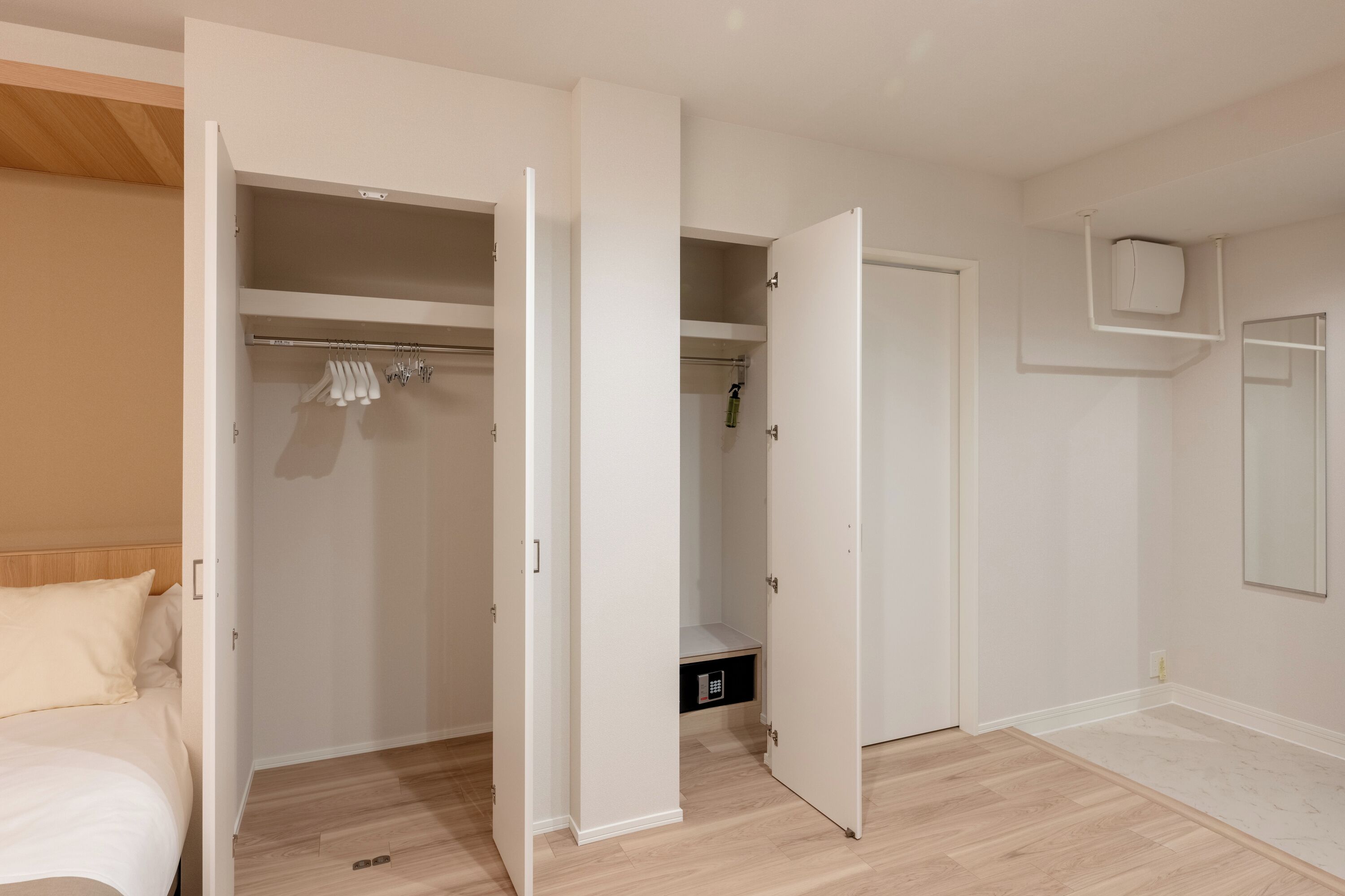 Une chambre à coucher avec un lit, une armoire où sont suspendus des vêtements, et une salle de bain avec une douche.