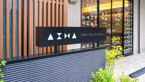 Une façade moderne d’un immeuble avec une enseigne indiquant « AIMA Tokyo Kinshicho ».