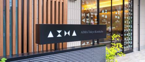 A modern building facade with a sign for AIMA Tokyo Kinshicho.