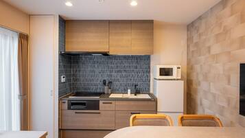 A compact hotel room with a kitchenette, a bed, and a seating area.