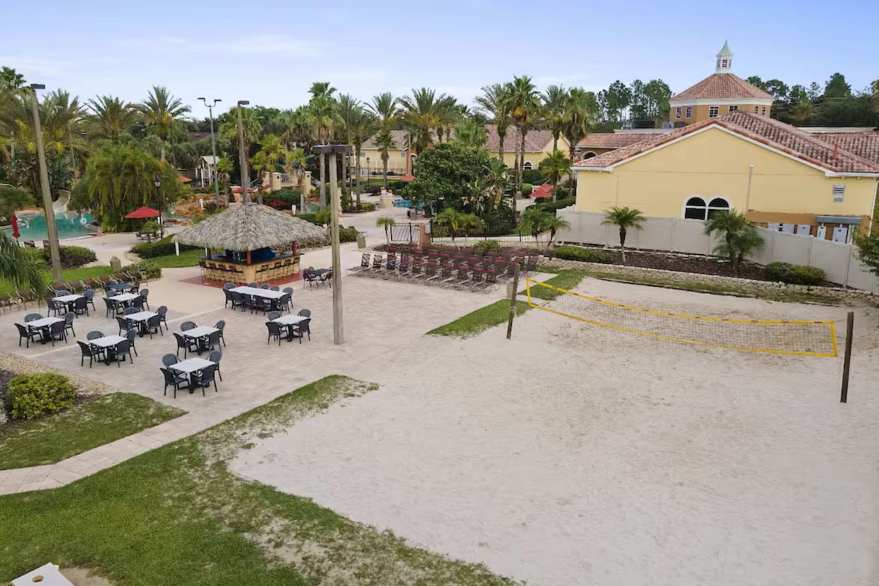 Una zona sulla spiaggia con posti a sedere all'aperto, una rete da pallavolo e un edificio con tetto rosso.