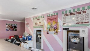 Un comptoir avec un tableau affichant le menu, un réfrigérateur et un mur orné d’une image d’enfants.