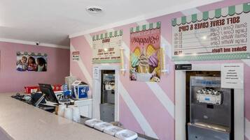 Un bancone con una lavagna dei menù, un frigorifero e una parete con una foto di bambini.