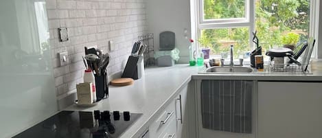 A modern kitchen with a built-in stove, white cabinetry, and a window providing a view of greenery outside.