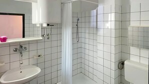 A bathroom with a white sink, a shower with a curtain, and a mirror above the sink. - 1 bedroom stunning apartment in Pula (Pula)