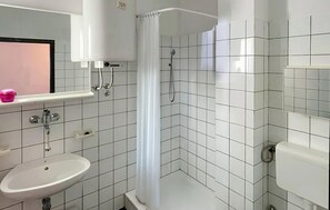 A bathroom with a white sink, a shower with a curtain, and a mirror above the sink. - 1 bedroom stunning apartment in Pula (Pula)