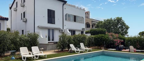 Un bâtiment à deux étages doté d’une piscine, d’un espace extérieur aménagé et d’un jardin bien entretenu.