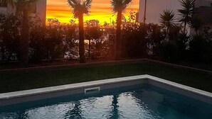 A swimming pool with a sunset view, surrounded by palm trees and a grassy area. - 1 bedroom stunning apartment in Pula (Pula)
