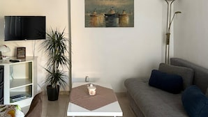 A living room with a sofa, a coffee table, a television, a plant, and a painting on the wall. - 1 bedroom stunning apartment in Pula (Pula)