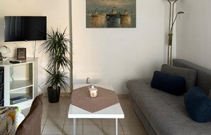 A living room with a sofa, a coffee table, a television, a plant, and a painting on the wall. - 1 bedroom stunning apartment in Pula (Pula)
