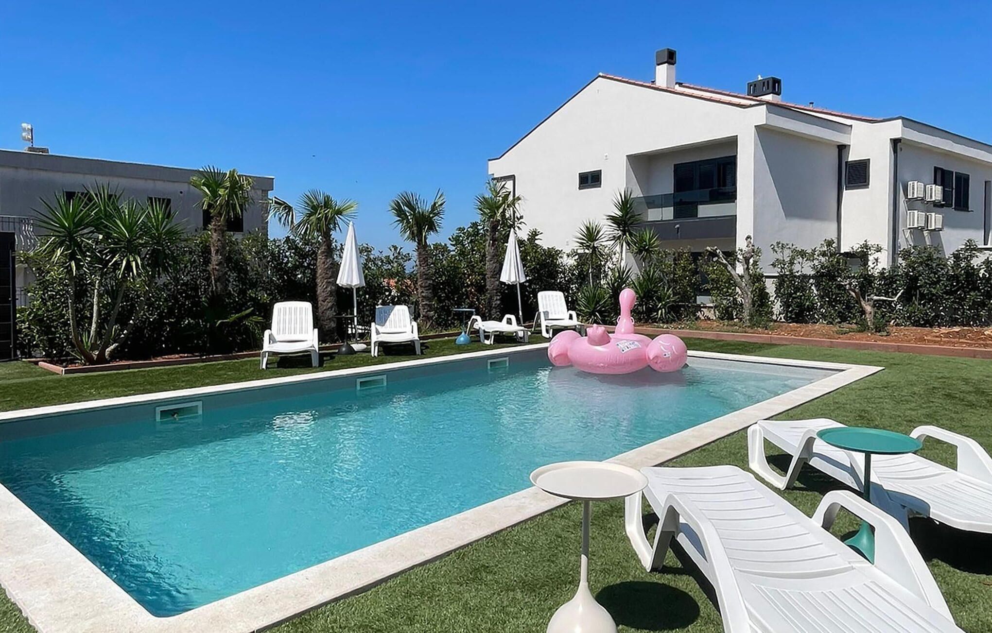 A swimming pool with lounge chairs and a pink flamingo float.