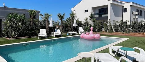 A swimming pool with lounge chairs and a pink flamingo float.