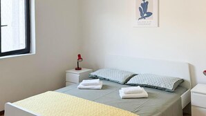 A bedroom with a bed, two pillows, a bedside table with a lamp, and a framed picture on the wall. - 1 bedroom stunning apartment in Pula (Pula)