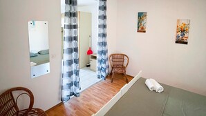 Een hotelkamer met een bed, een stoel, een spiegel en een deur naar een badkamer.