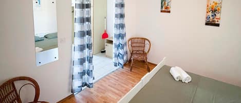 A hotel room with a bed, a chair, a mirror, and a door leading to a bathroom.