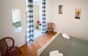 A hotel room with a bed, a chair, a mirror, and a door leading to a bathroom. - Cozy apartment in Pula with outdoor swimming pool (Pula)
