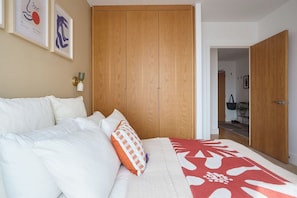 A bedroom with a bed, a wardrobe, and a door leading to another room. - Entire 2 bed, 2 bath near Canning Town & River (Greater London)