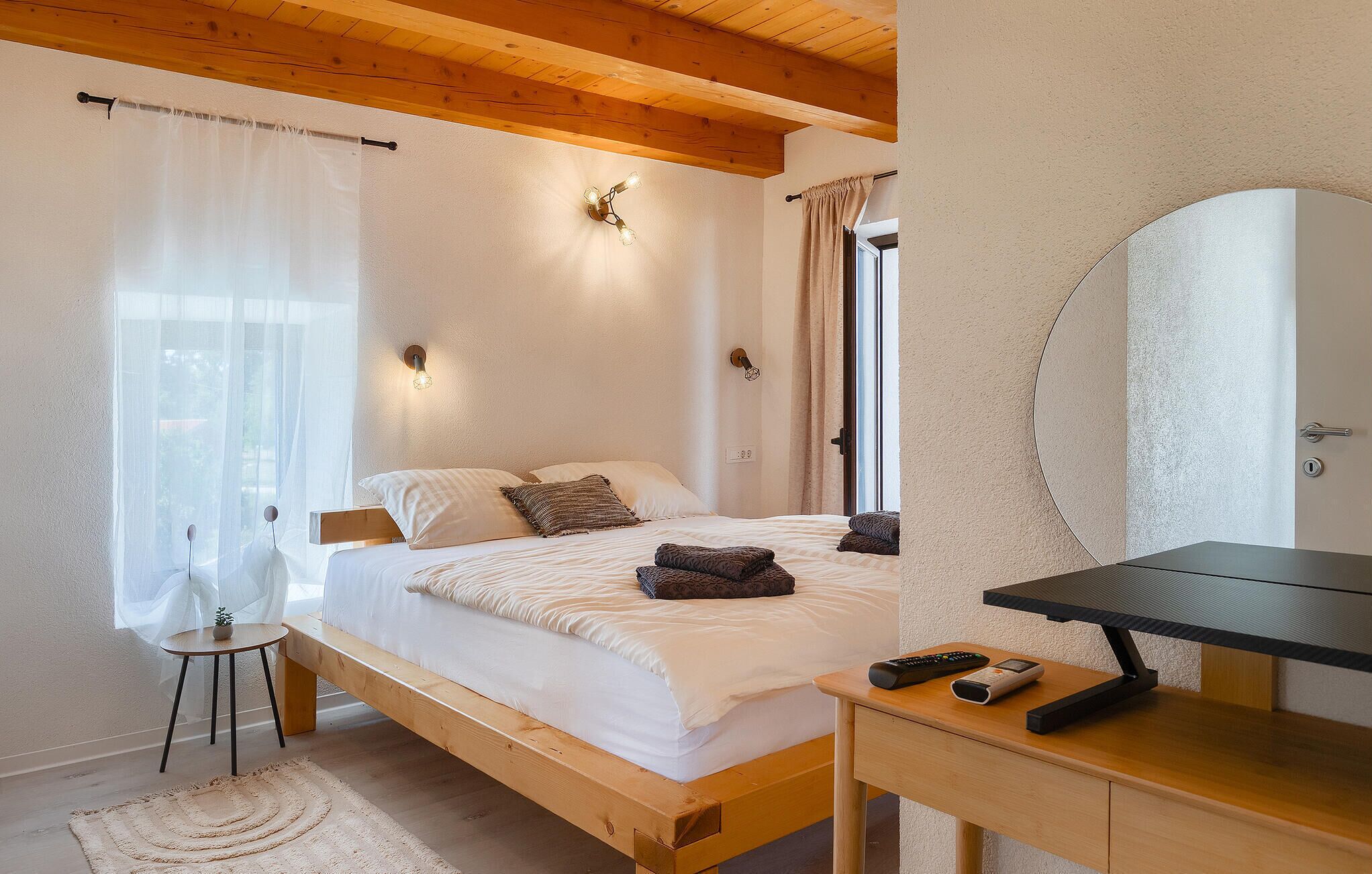 Un dormitorio con cama de madera, mesita de noche y espejo.
