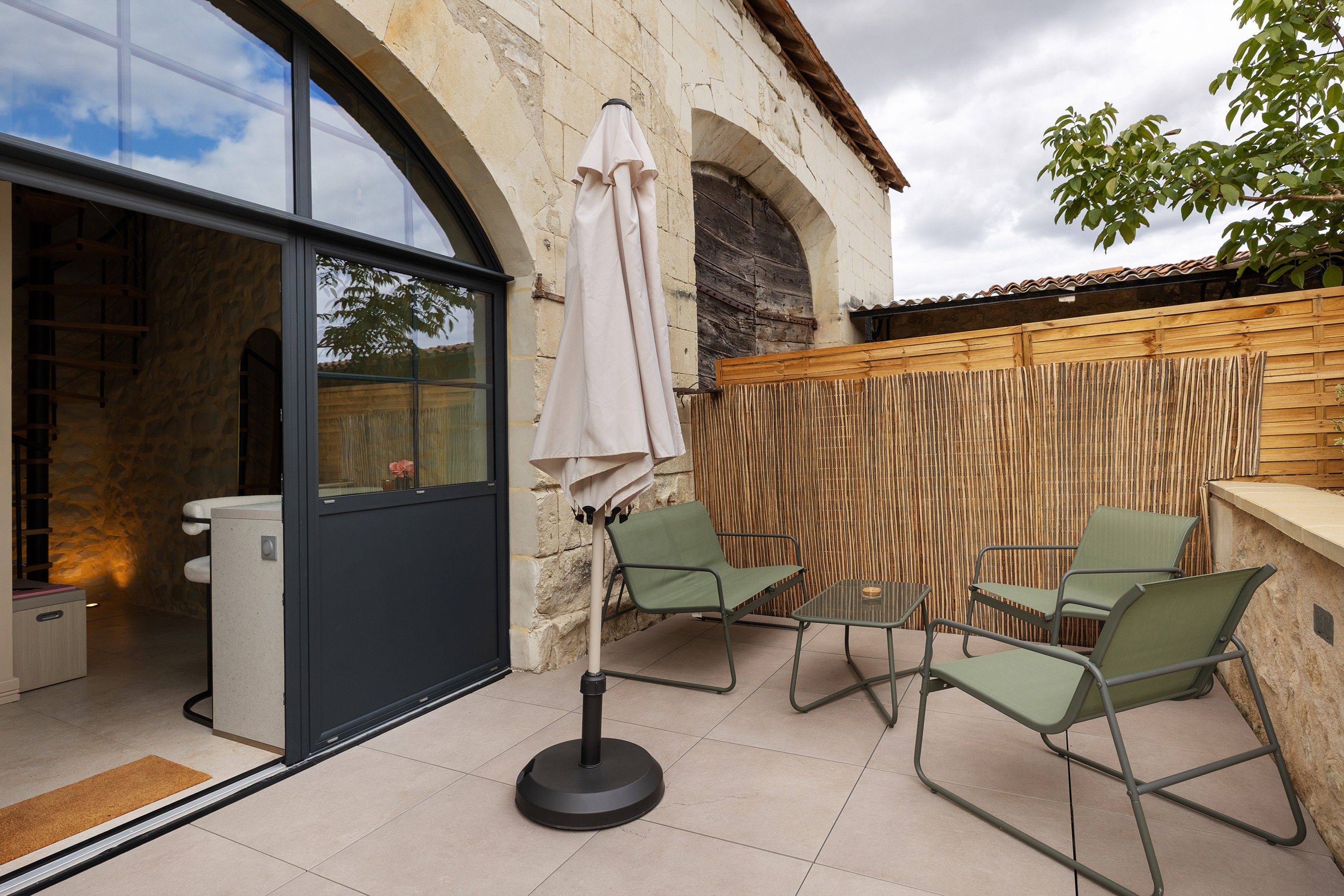 A patio area with a table and chairs, a covered umbrella, and a stone wall.