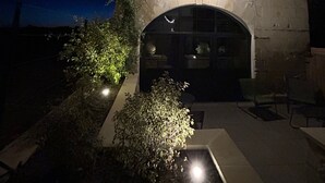 A stone building with a large arched entrance and a garage. There are string lights above the entrance and a small window on the upper wall. - Holiday Home “Le Pigeonnier Des Châpeaudieres” with Private Terrace, Wi-Fi, Air Conditioning (Châtellerault)