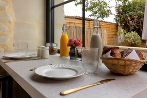 A breakfast setup with a plate, glass, jug, and basket of bread. - Holiday Home “Le Pigeonnier Des Châpeaudieres” with Private Terrace, Wi-Fi, Air Conditioning (Châtellerault)