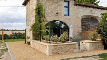 Un bâtiment en pierre doté d’une grande fenêtre en arc de cercle, d’un petit balcon et d’une porte en bois.