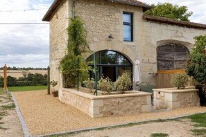 A stone building with a large arched window, a small balcony, and a wooden door.