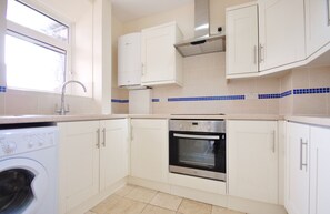 A kitchen with white cabinets, a stainless steel oven, a washing machine, and a window. - 2BDR 2BA Peckham Rye Flat with Park Access (Greater London)