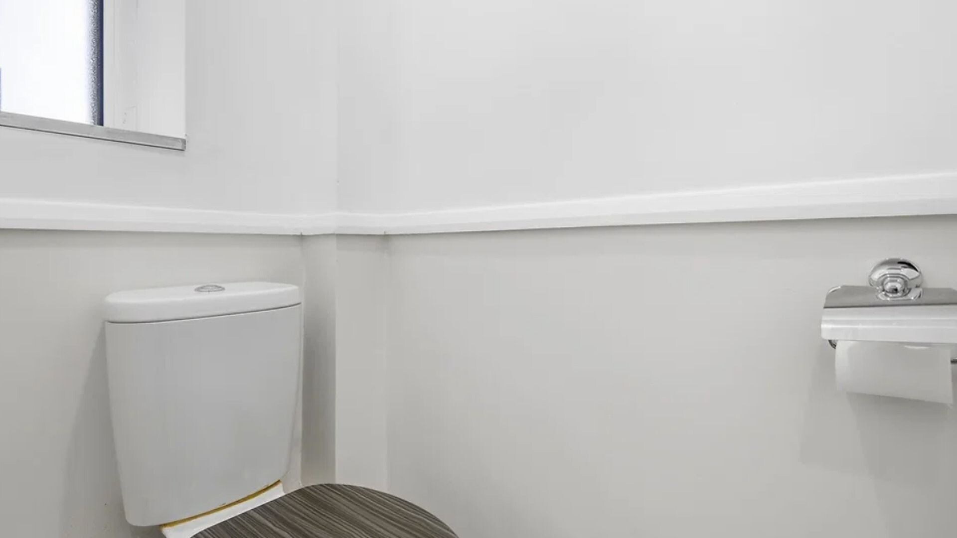 Eine weiße Toilette, ein weißes Waschbecken und ein Spiegel an der Wand in einem Badezimmer.