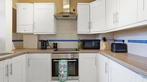 A kitchen with white cabinets, a microwave, a toaster, and a kettle. - 2BDR 2BA Peckham Rye Flat with Park Access (Greater London)