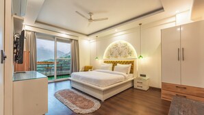 A bedroom with a bed, bedside tables, a wardrobe, a ceiling fan, and a view of the outdoors. - Aloha On The Ganga Almost Heaven 2BR Condo With Pool (Rishikesh)