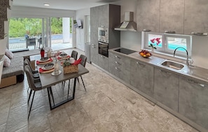 Eine moderne Küche mit Essbereich, ausgestattet mit Backofen, Mikrowelle und einem großen Fenster mit Aussicht.