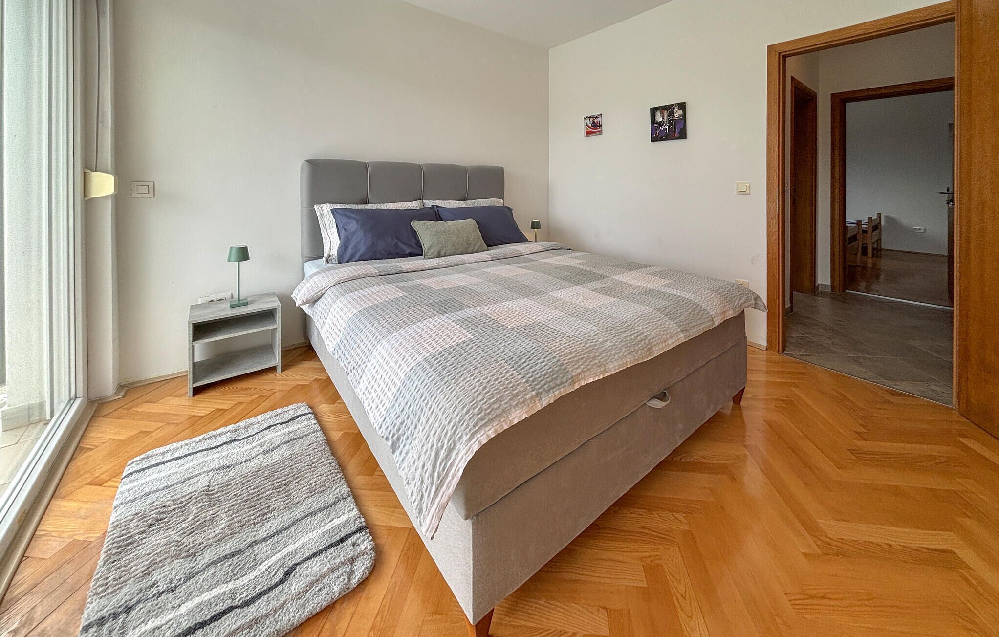 A bedroom with a bed, bedside table, lamp, and a rug.