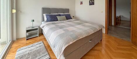 A bedroom with a bed, bedside table, lamp, and a rug.