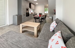 Ein modernes Wohnzimmer mit einer Couch, einem Couchtisch und einem Essbereich mit Stühlen und Tisch.